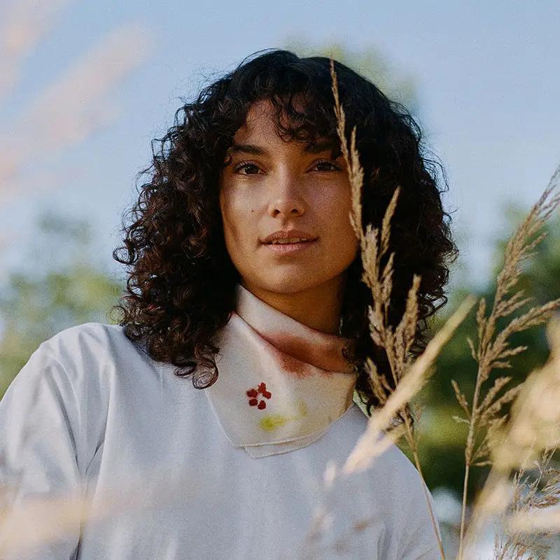 Young woman with dark curly hair in a pampa field