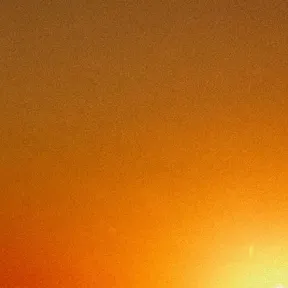 A silhouette of an industrial structure is contrasted against a vibrant sunset, with shades of orange and yellow blending into a warm sky.